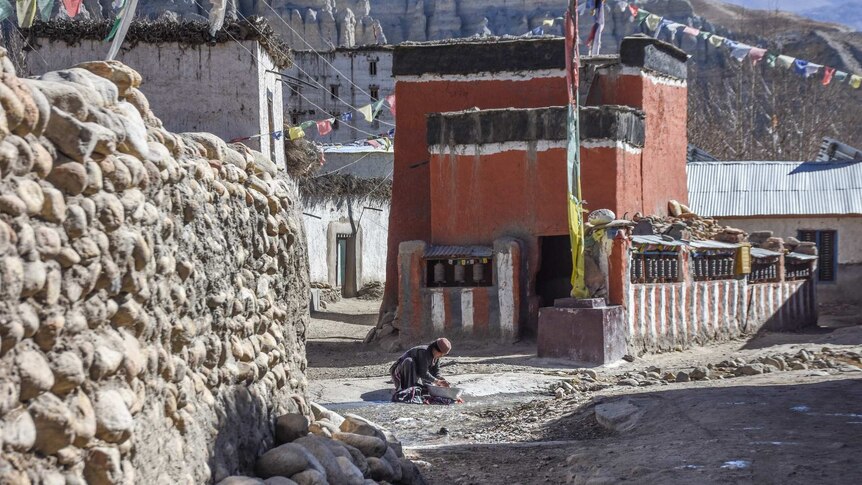 Woman cleans her clothes in a basin in the street