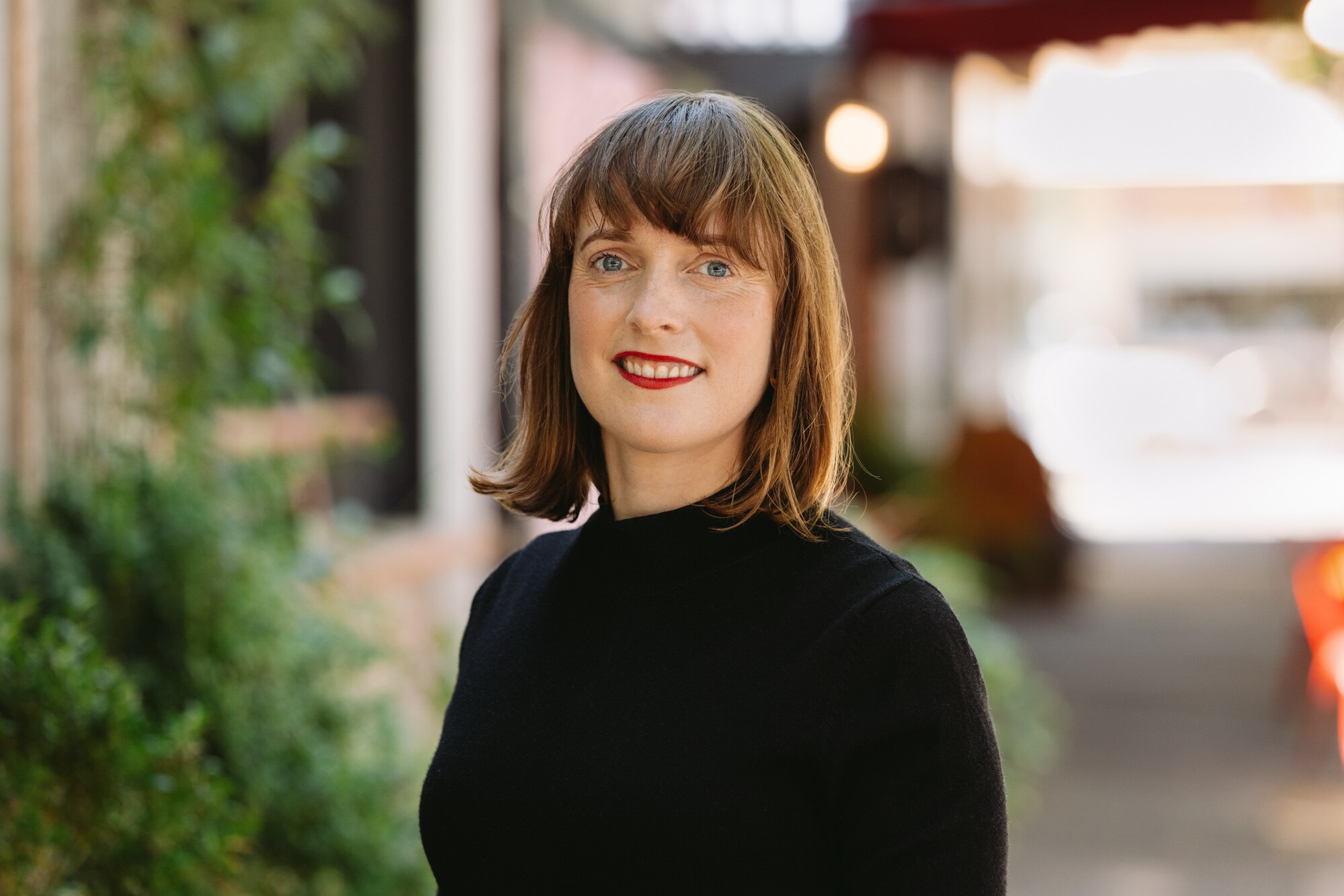 Una imagen de primer plano de una mujer con cabello castaño, sonriendo a la cámara.