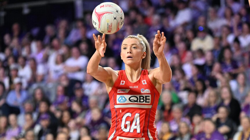 A NSW Swifts Super Netball player passes the ball during a game against the Queensland Firebirds.