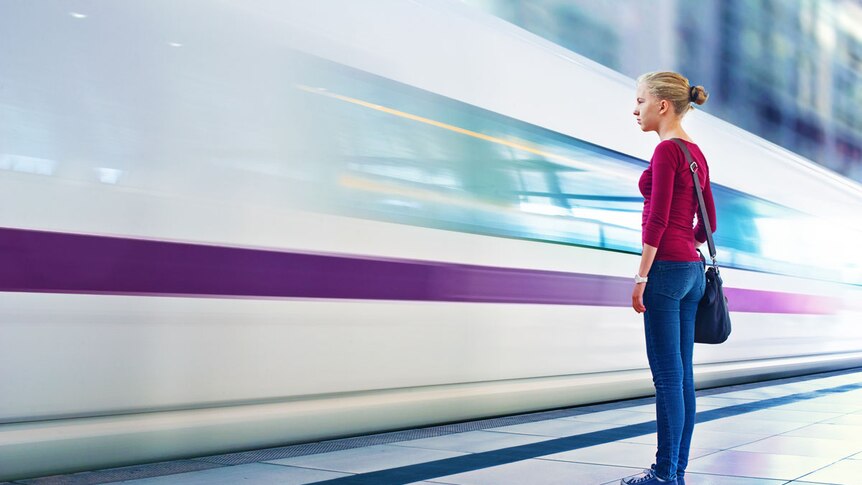 A girl standing close the a fast passing train