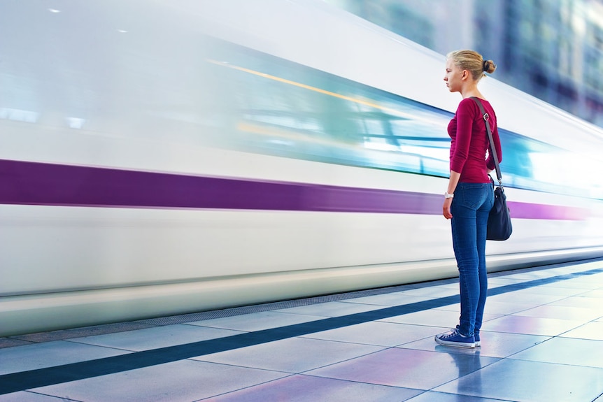 A girl standing close the a fast passing train