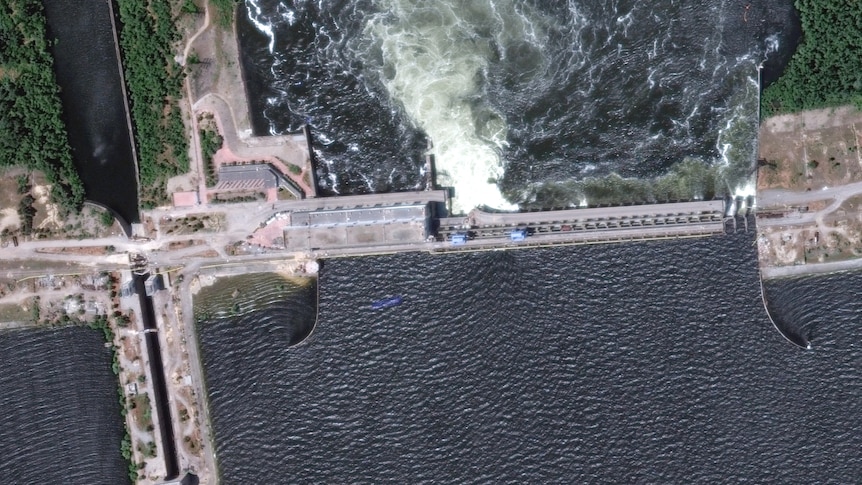 A satellite view of dam with gushing water.