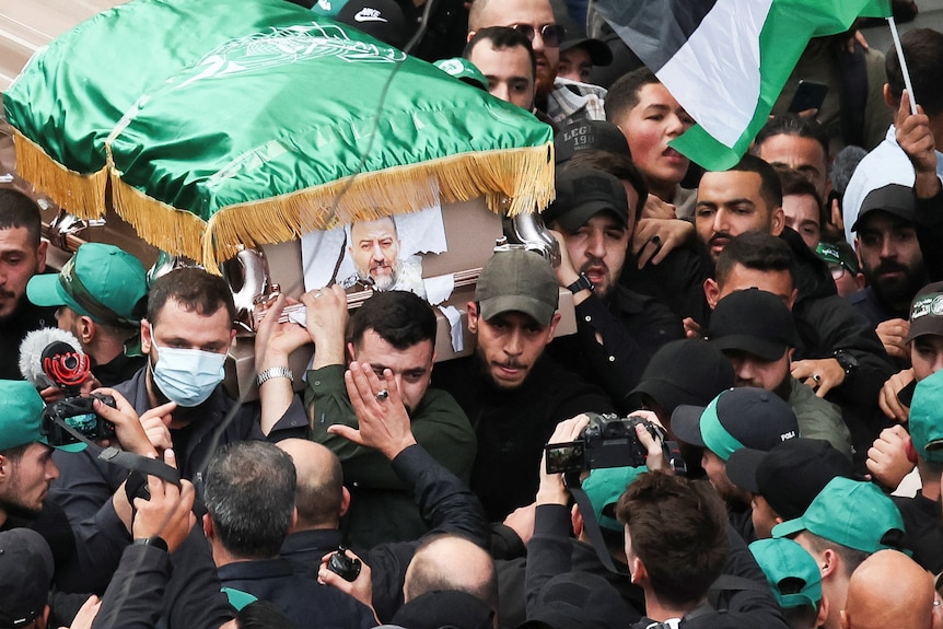 A large crowd gathered around a casket with a man's face on it. 