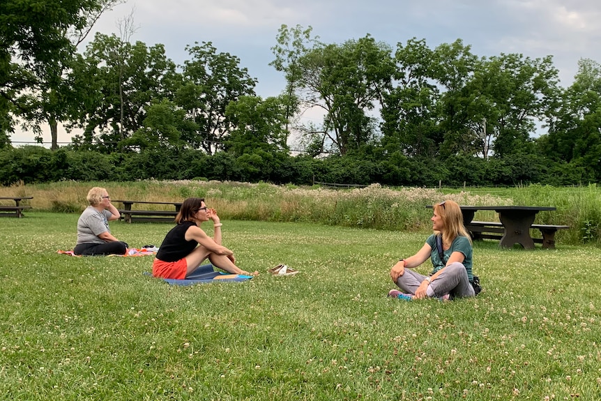 Three people sitting in a field. 