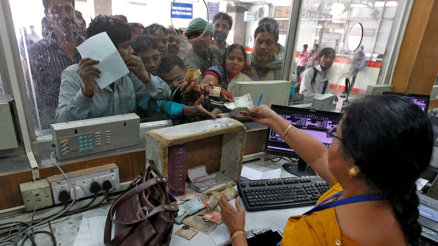 People pay for train ticket with abolished rupee notes before they can no longer be used.