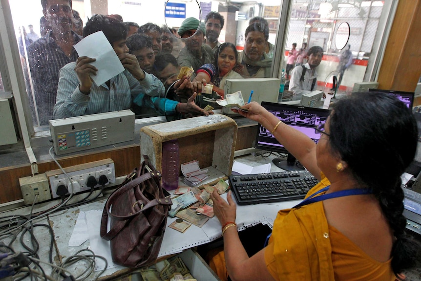 People pay for train ticket with abolished rupee notes before they can no longer be used.