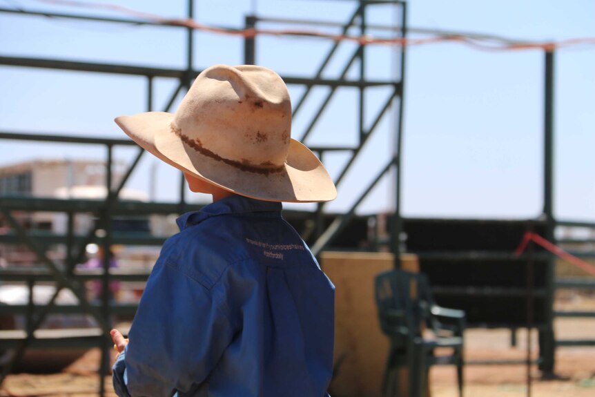 A young boy in an Akubra watches on.