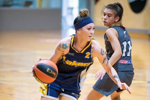 A female basketball player defends off an opposing player