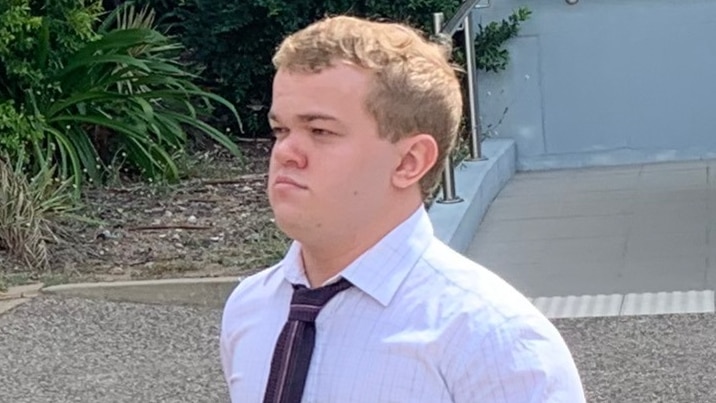 Photo of young man in white shirt with black dress tie walking away from camera.