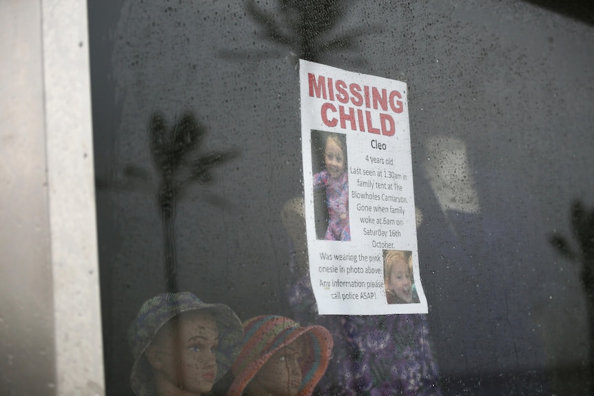 Two children looking through a window with a poster of Cleo stuck on
