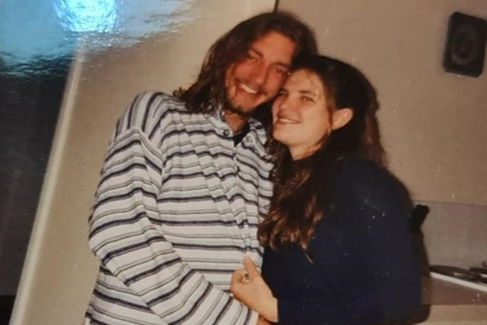 a young man and woman embracing in a kitchen