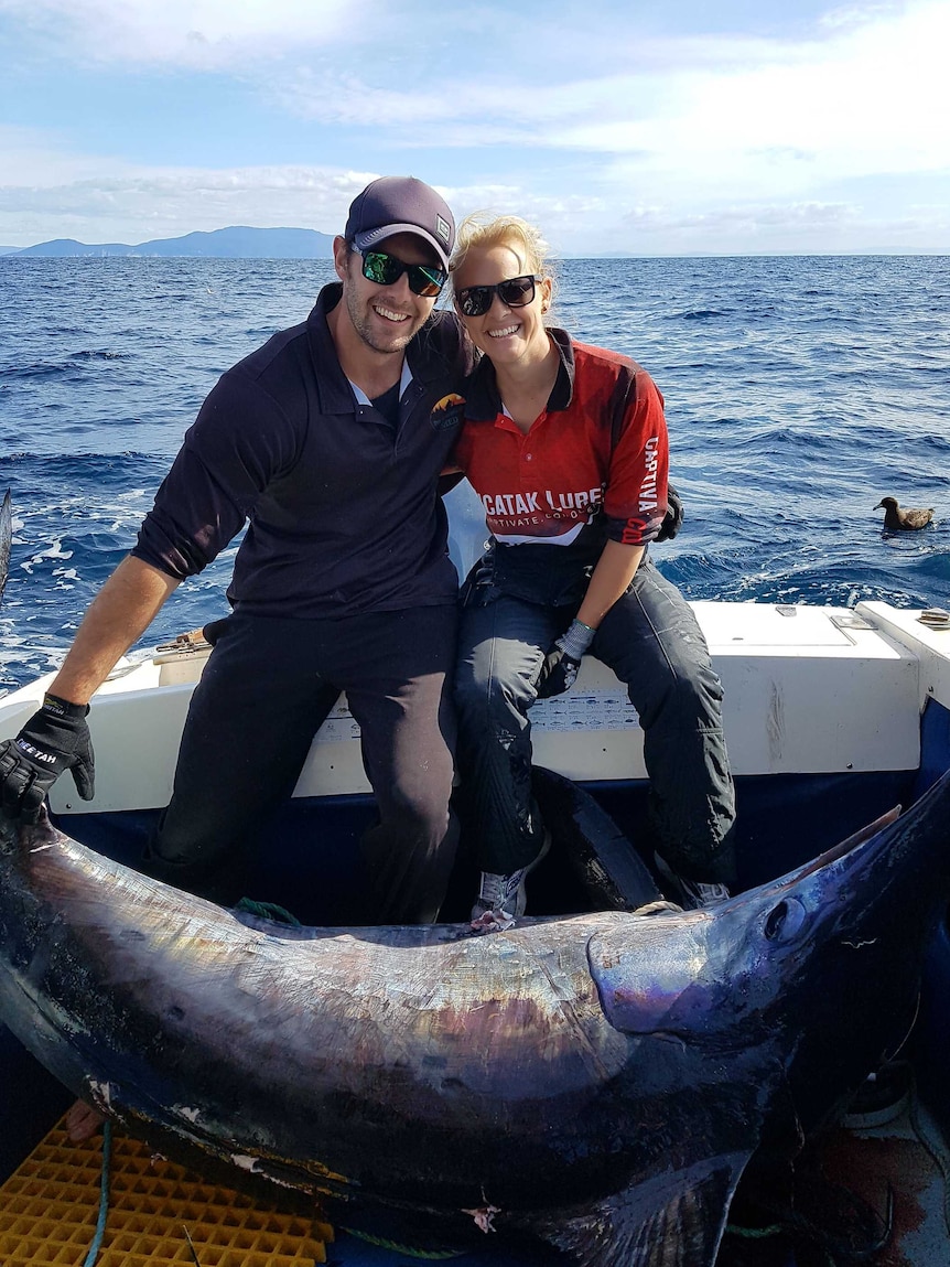 Naomi Wisby and husband Brody Corbett on a boat with a large swordfish.