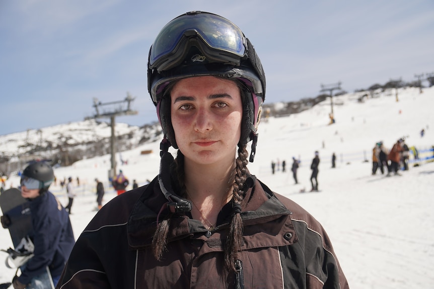 A young woman looks seriously into the camera with snowgear on.