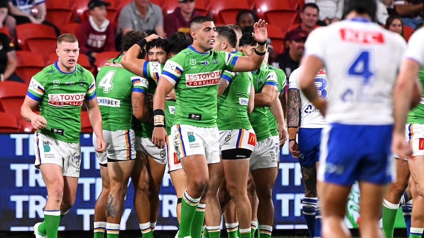 Canberra Raiders players gather together to celebrate a try in an NRL Magic Round game against Canterbury Bulldogs.