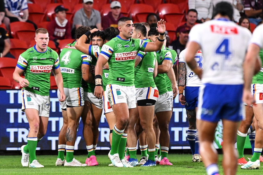 Canberra Raiders players gather together to celebrate a try in an NRL Magic Round game against Canterbury Bulldogs.