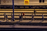 Migrants walk along railway tracks at the Eurotunnel terminal in Calais-Frethun