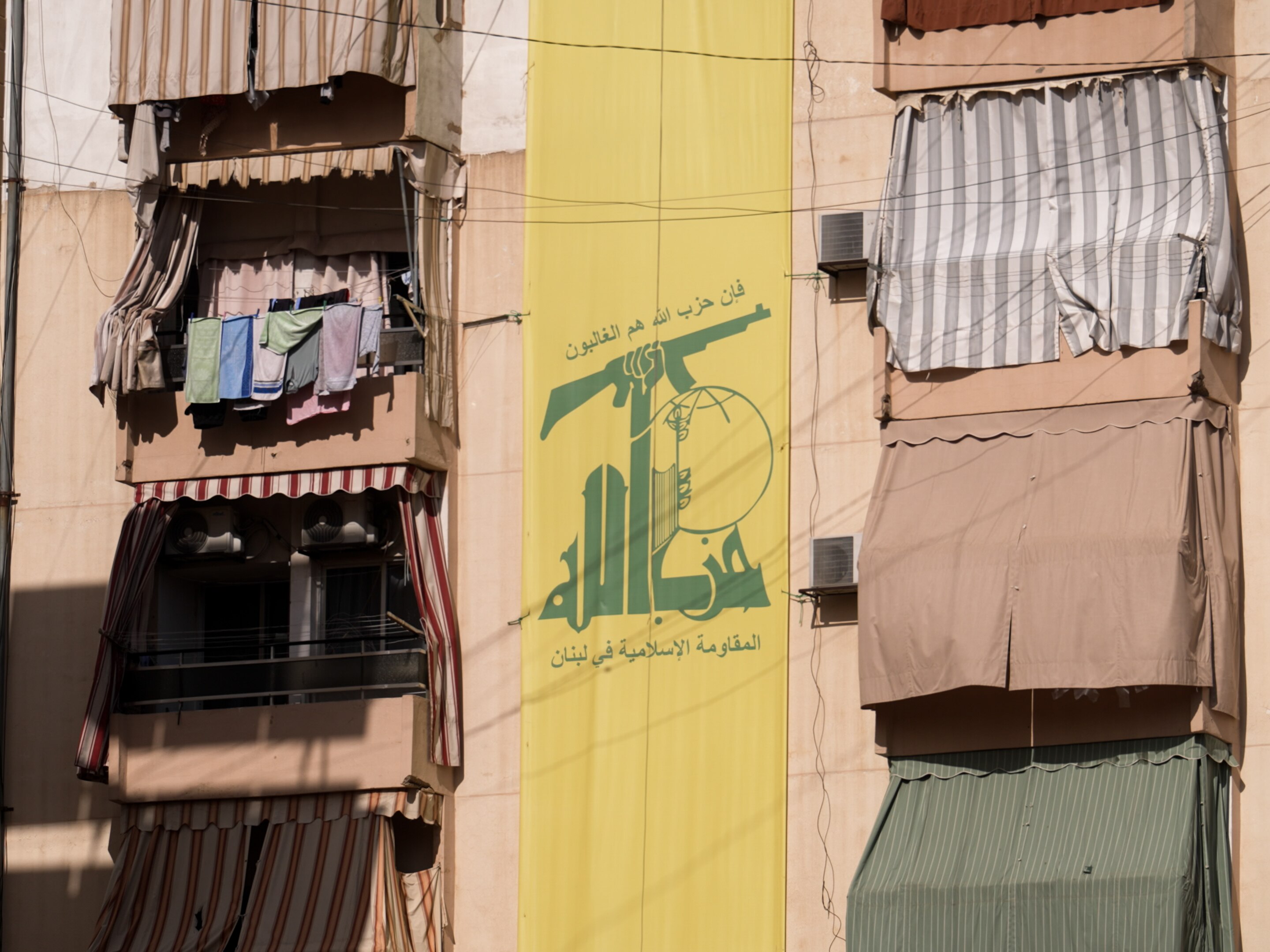 A yellow banner with a green sign symbolising Hezbollah hangs on a building.