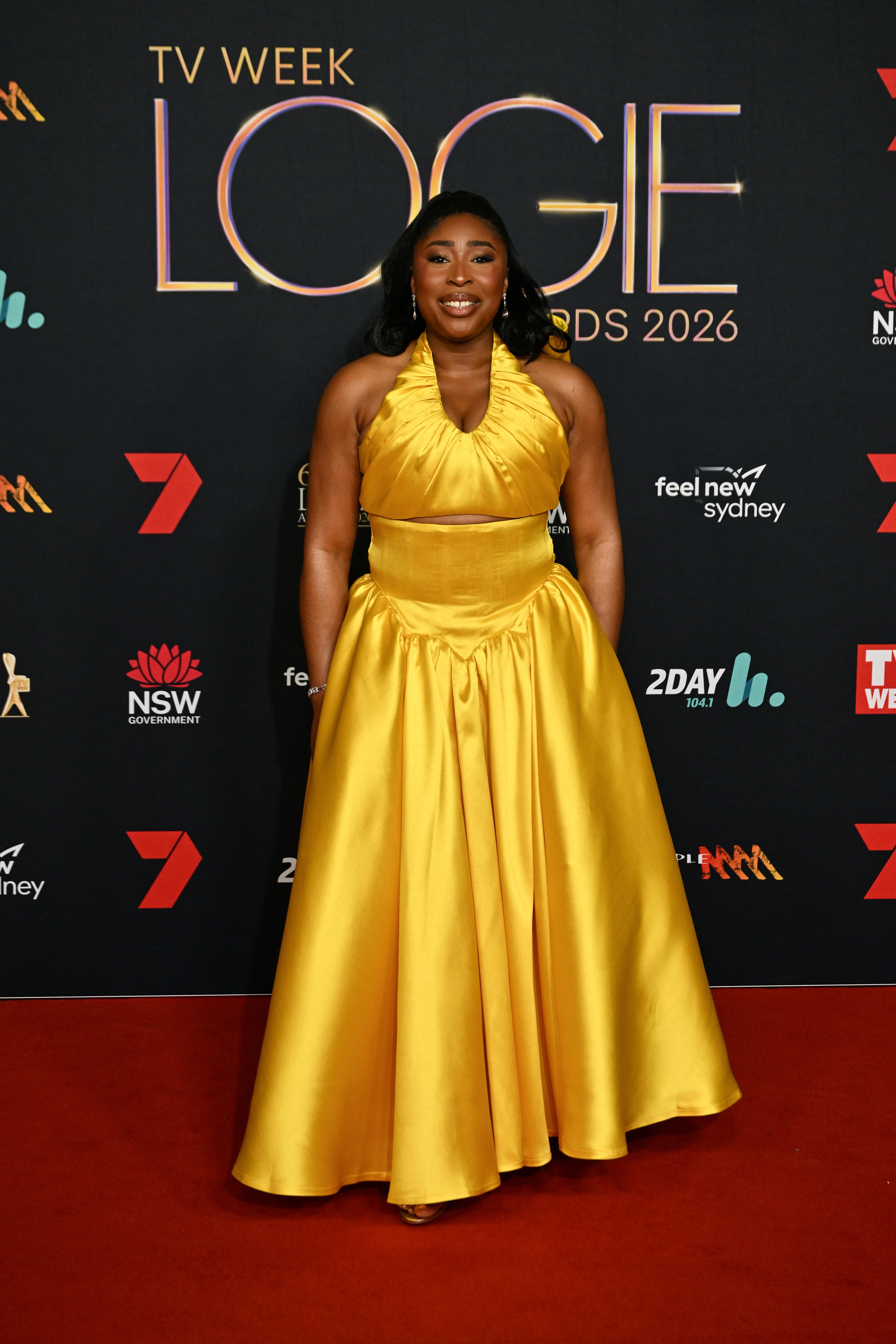 Ikogwe wears a sunflower yellow halterneck dress with a full skirt.