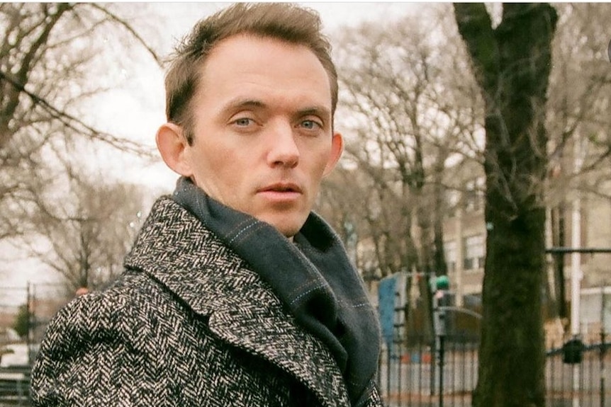 Mark Dessaix looks at the camera in Central Park wearing a winter coat. 