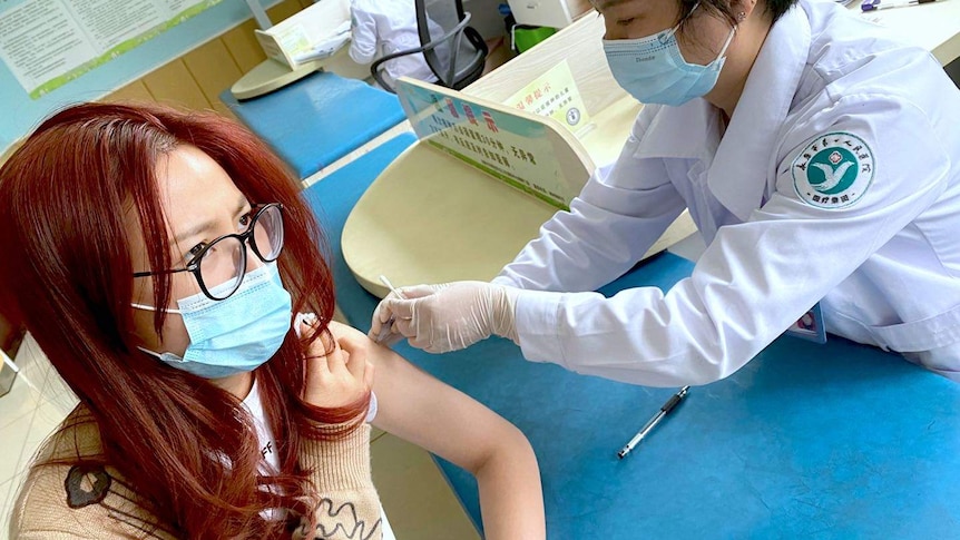 A woman receiving a vaccine for COVID-19 in a hospital.