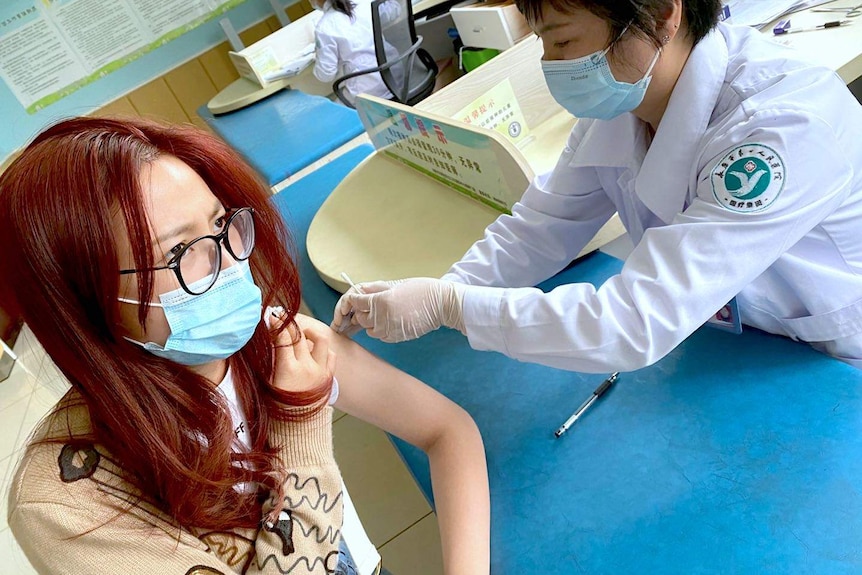 A woman receiving a vaccine for COVID-19 in a hospital.