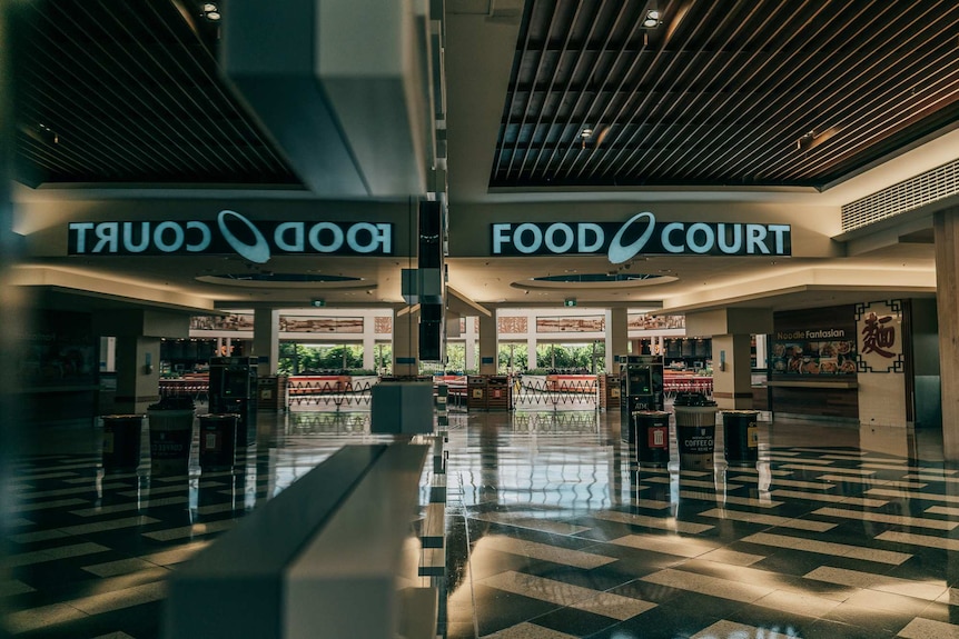 An empty shopping centre and food court sign as reflected off a wall.