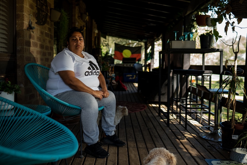 A woman sits on a chair on a balcony.