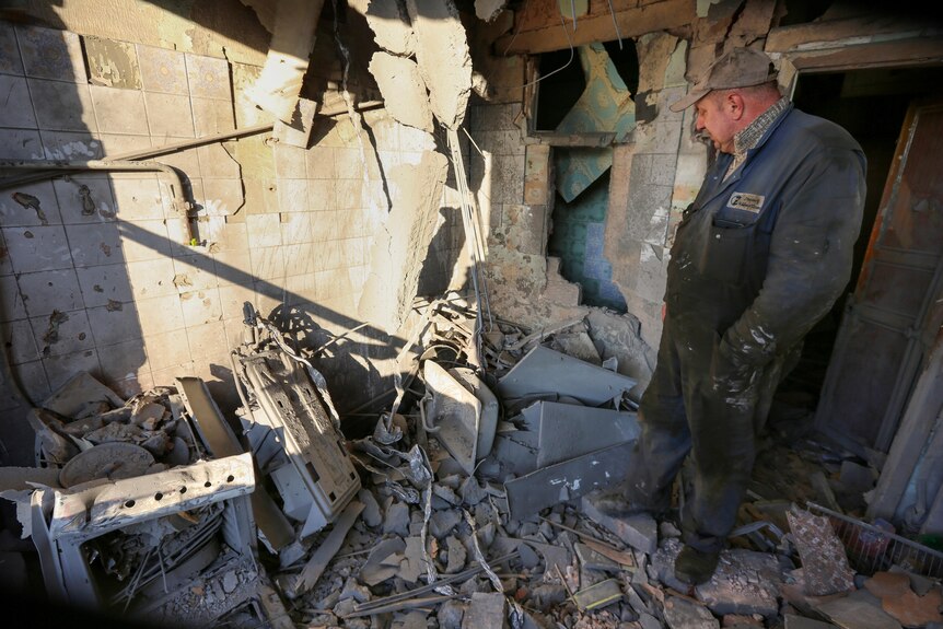 A man examines a damaged apartment building