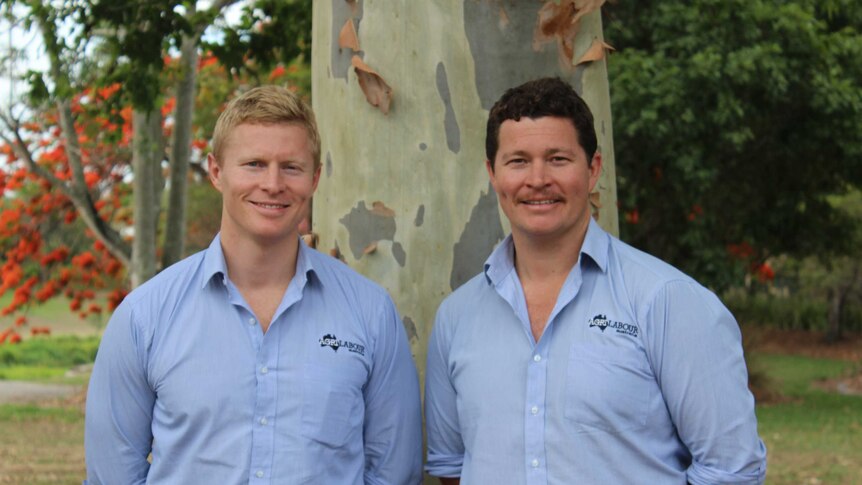 Casey and Luke Brown stand next to each other, gumtree in background