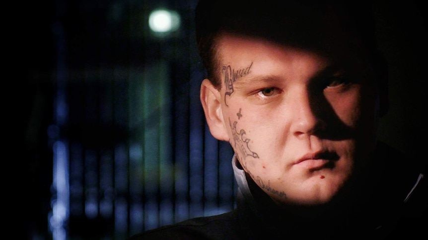 Close up of a young man with face tattoos pictured inside a prison