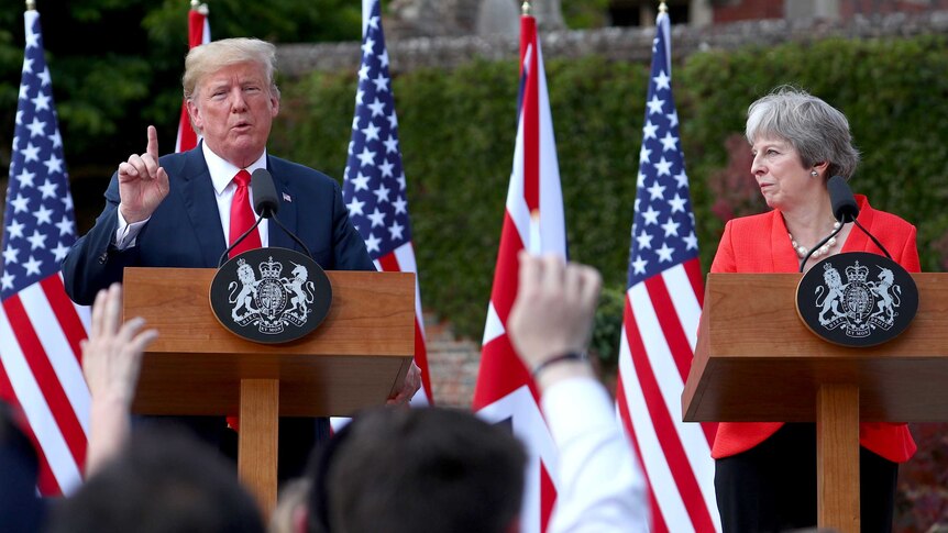 Trump and May stand at podium while Trump speaks at a press conference