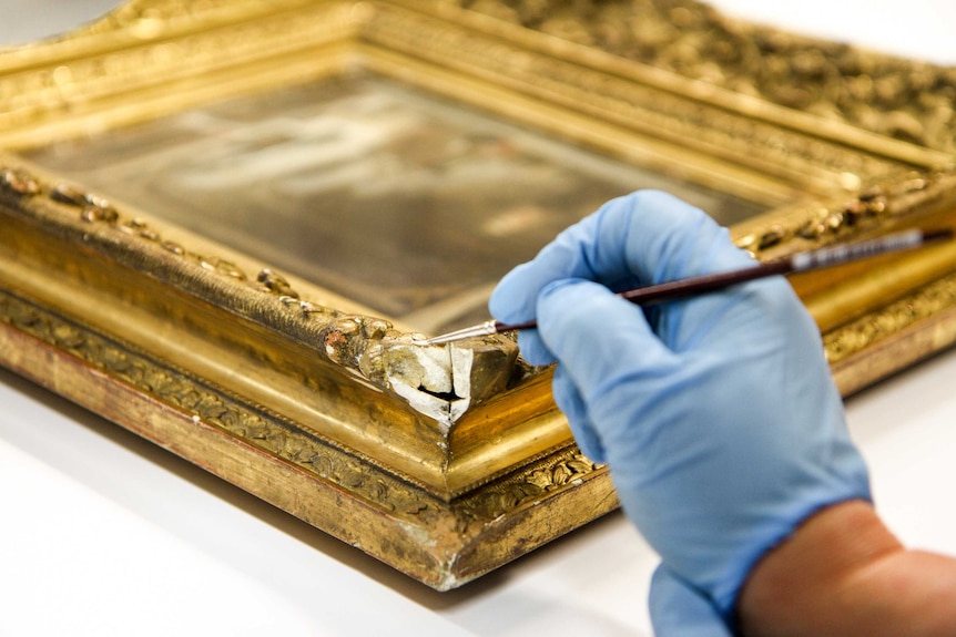 A damaged corner of a gold frame.