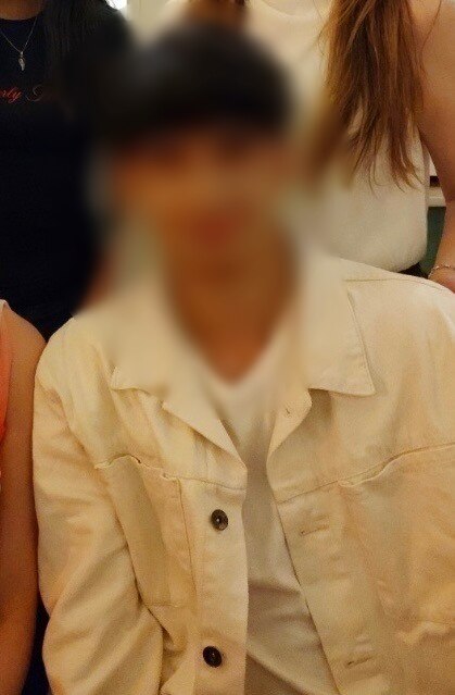 A teenager smiling while earing a white jacket.