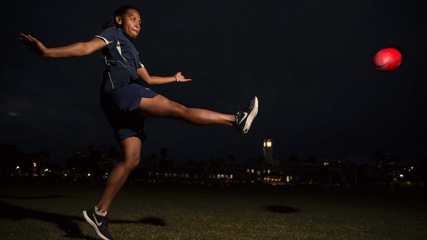 Matelita Tuilevuka kicks an AFL football at night time in Suva.