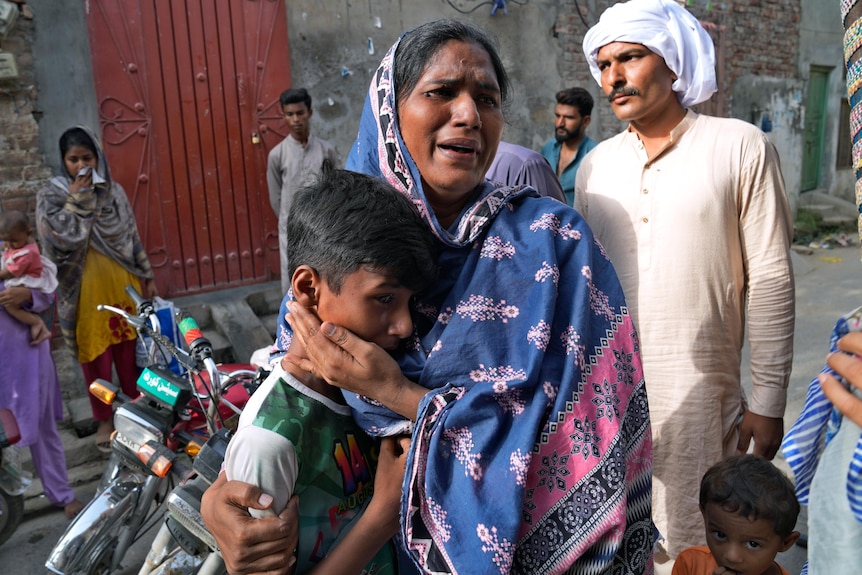 A Christian woman and a boy weep after seeing their homes vandalized by angry Muslim mob .