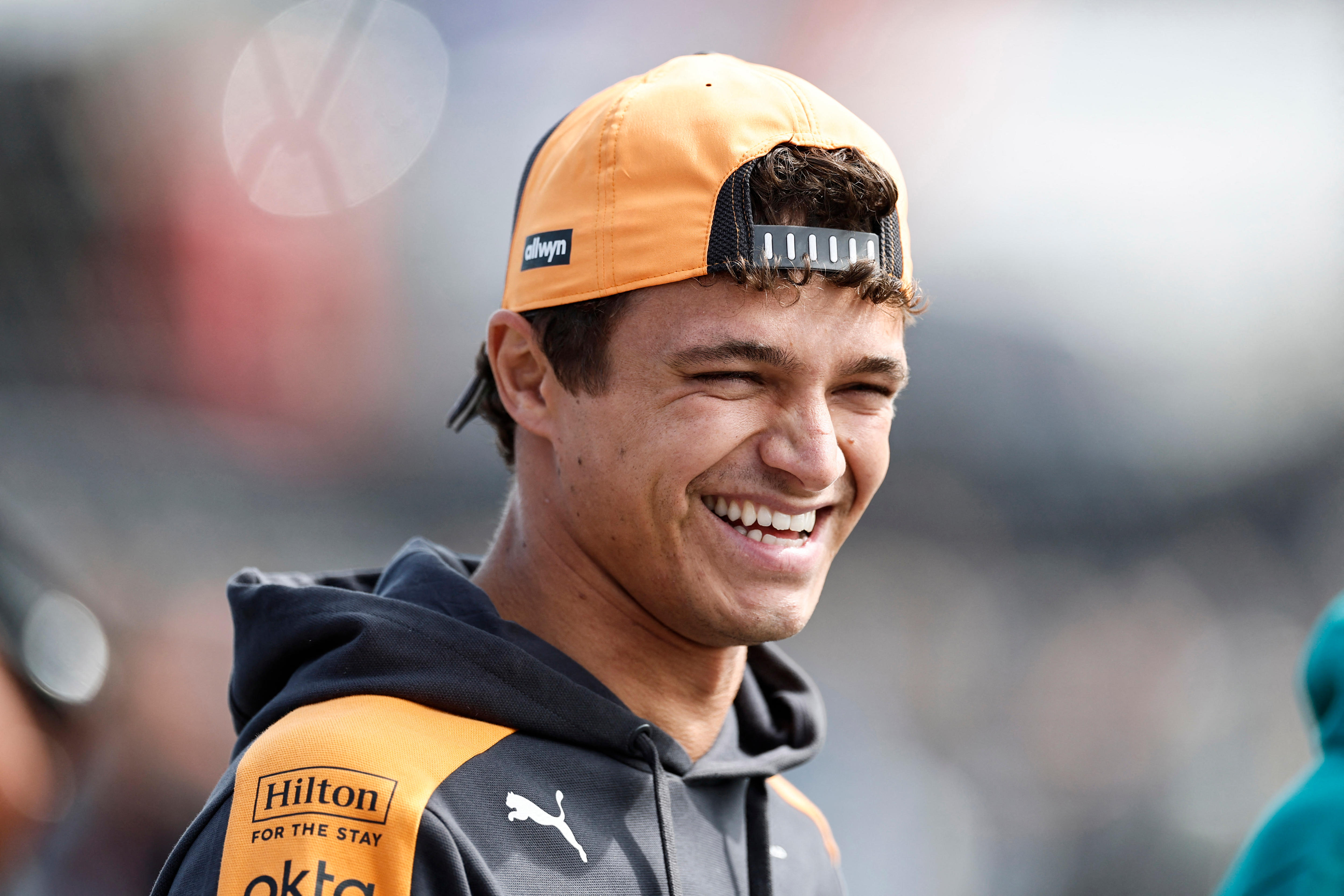 McLaren driver Lando Norris smiling in casual racing attire before a race