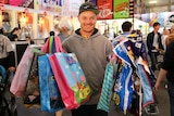 A man with a large collection of showbags from the Brisbane Ekka