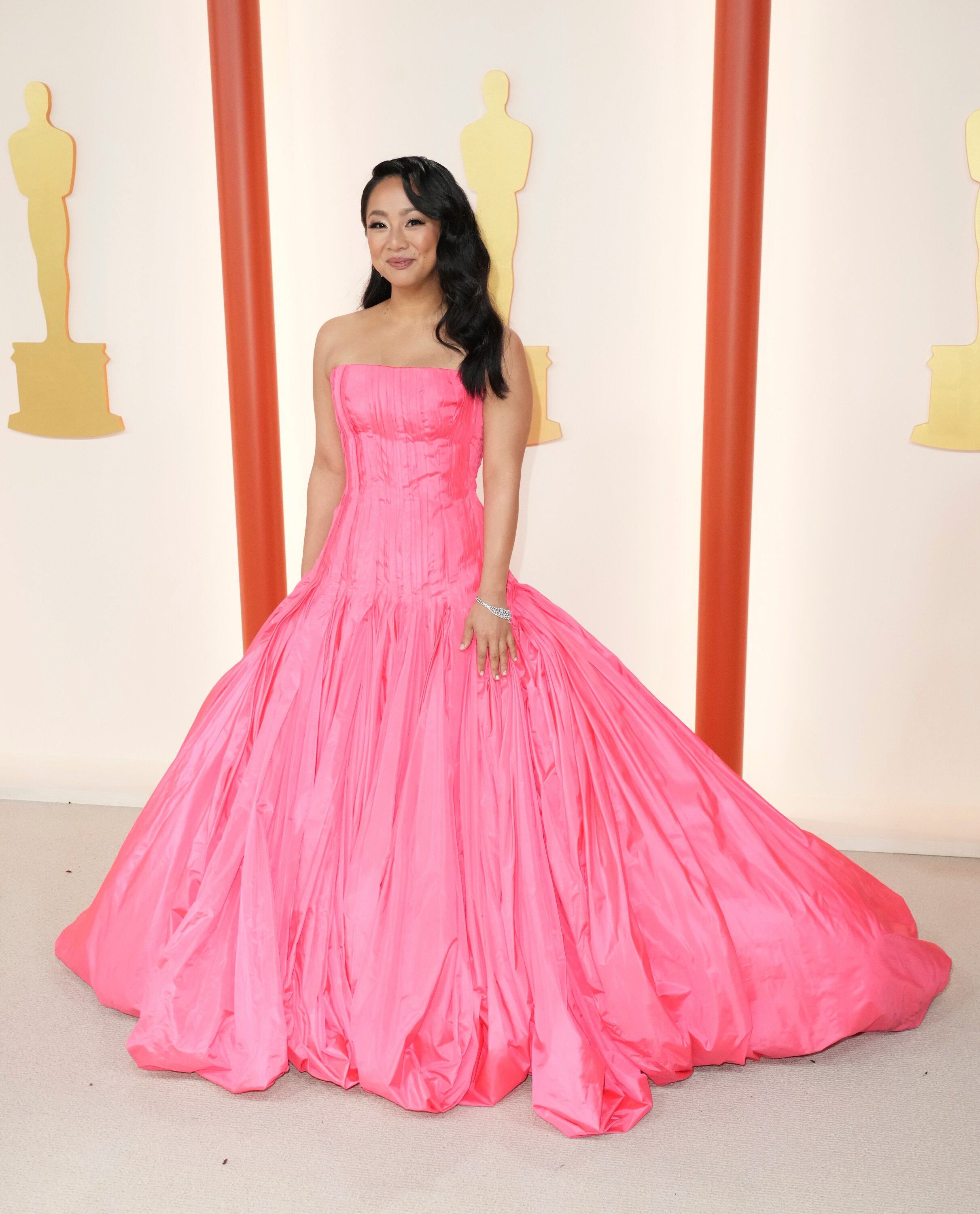 Stephanie Hsu wearing a bright pink strapless gown with a full skirt with lots of ruching