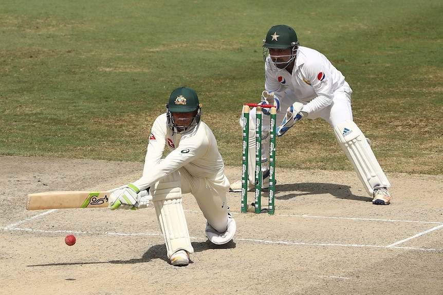 Telephoto shot of a cricketer playing a reverse sweep shot.