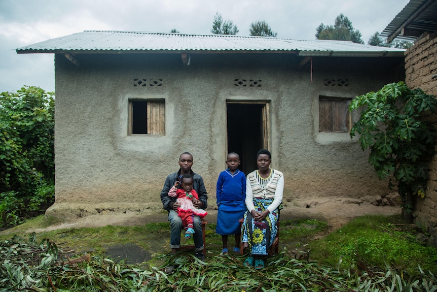 Emmanuel and his family sit out the front of their house in Rwanda.