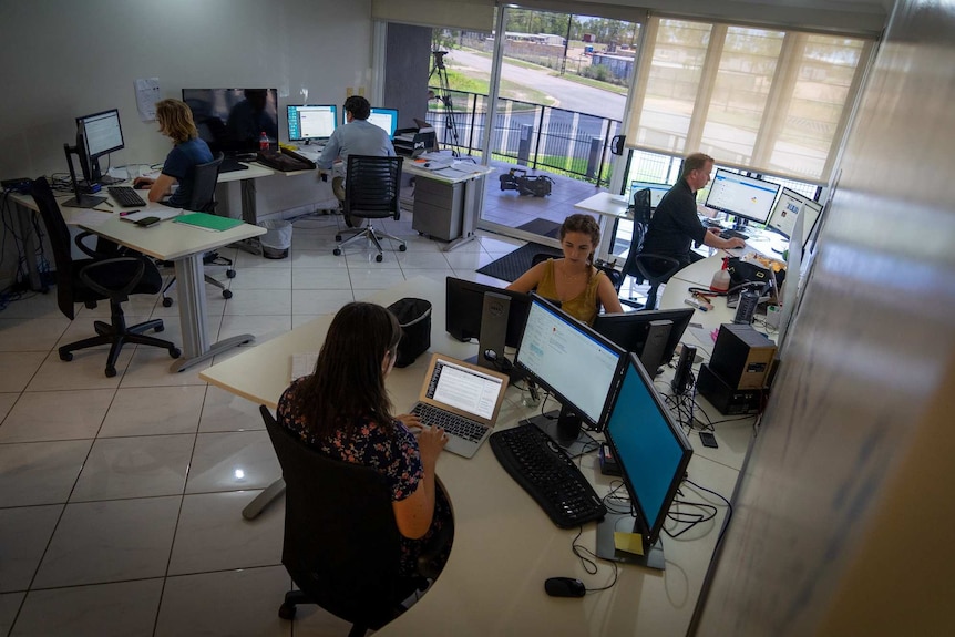 Five journalists sit at their desks at the NT Independent's newsroom.