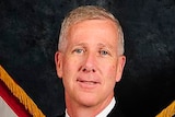 A man with pale grey hair wearing a former naval uniform.