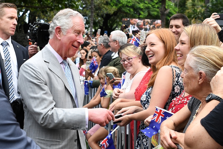 The then Prince of Wales smiles in a grey suit as he meets scores of women in Brisbane.