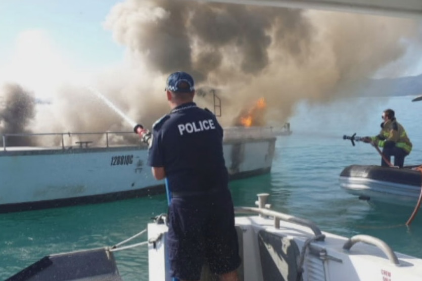 Police douse a fire on a boat after an explosion at Airlie Beach in April 2015
