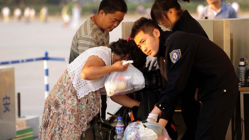 Security staff search visitors' belongings at an entrance to Tiananmen Square