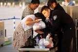 Security staff search visitors' belongings at an entrance to Tiananmen Square