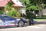 a police officer kneels down taking a photo of the front of a marked highway patrol police vehicle parked in a suburban street