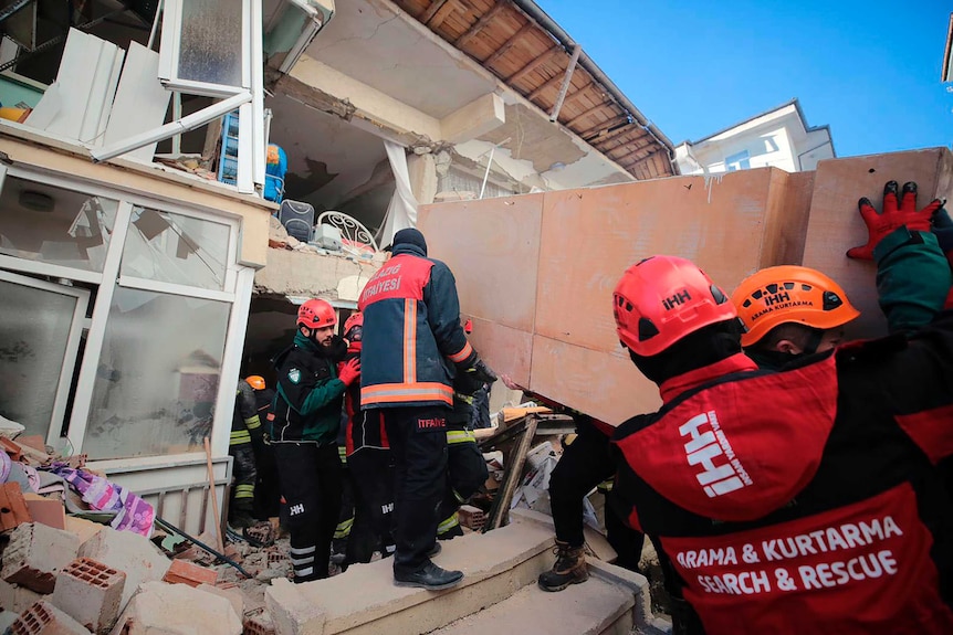 Rescuers work on searching for people buried under the rubble on a collapsed building in Elazig.