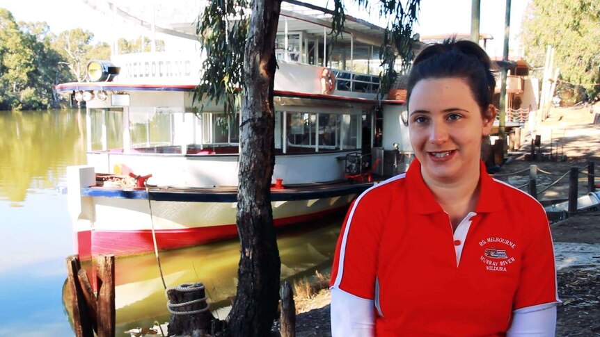 Ashton Kreuzer on the deck of a paddle vessel with the PV Rothbury and the Murray River visible in the background.