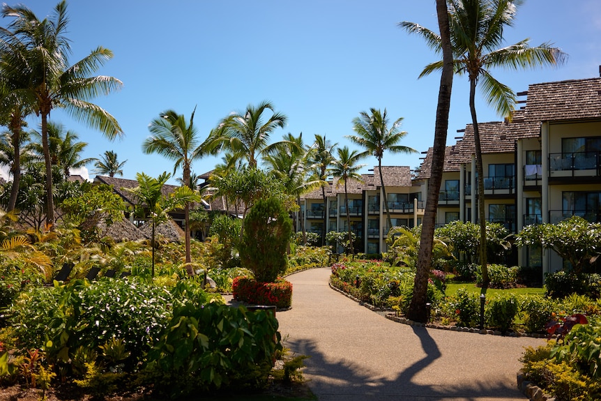 A palm-tree-lined path weaves its way through locks of villas at a Fijian resort